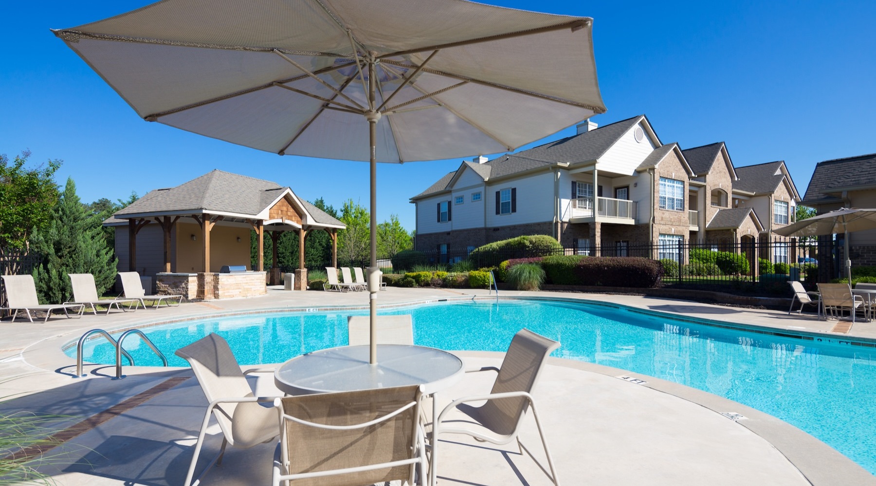a swimming pool with a table, chairs and an umbrella